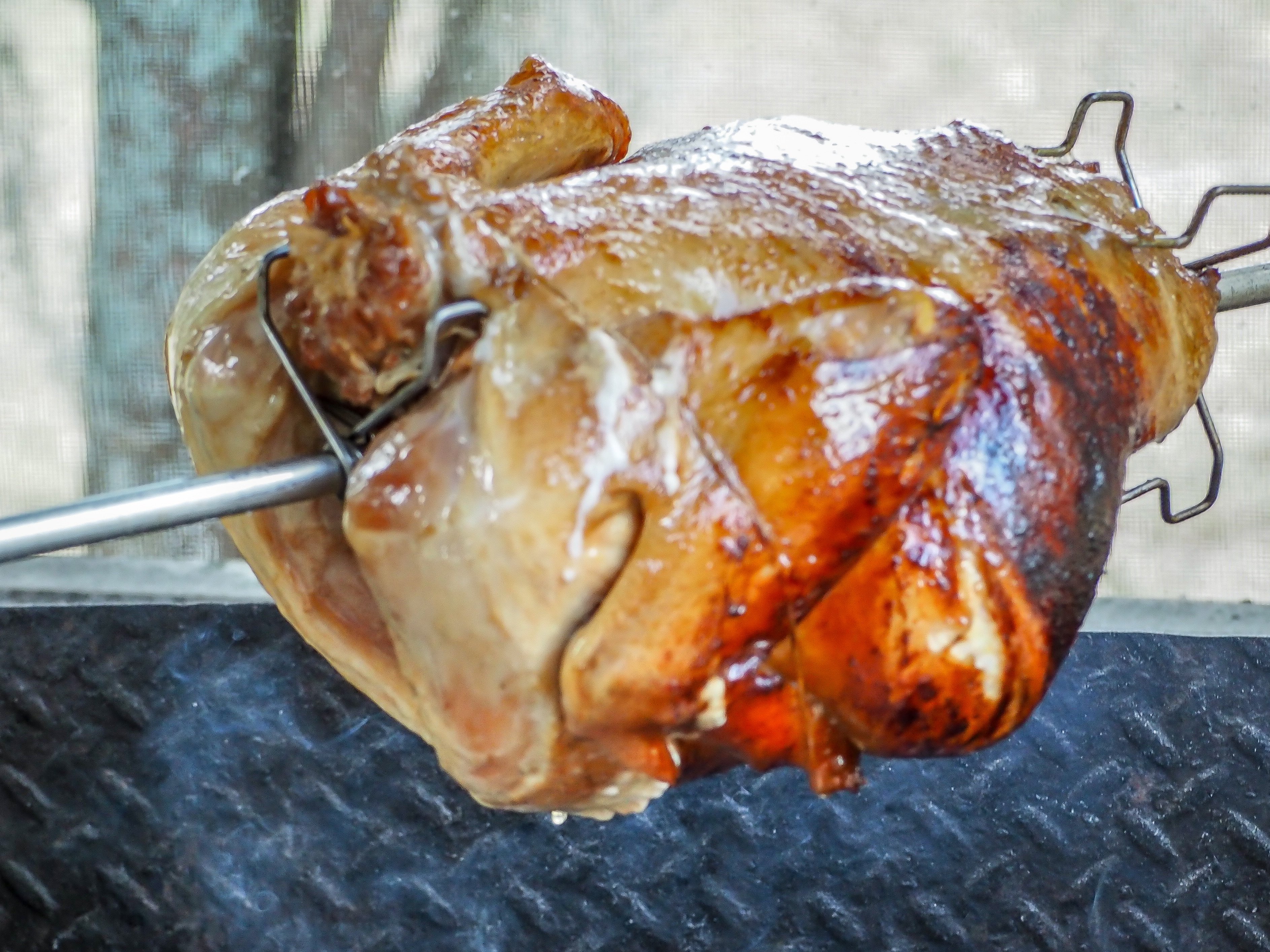turkey cooking over an open fire on a rotisserie