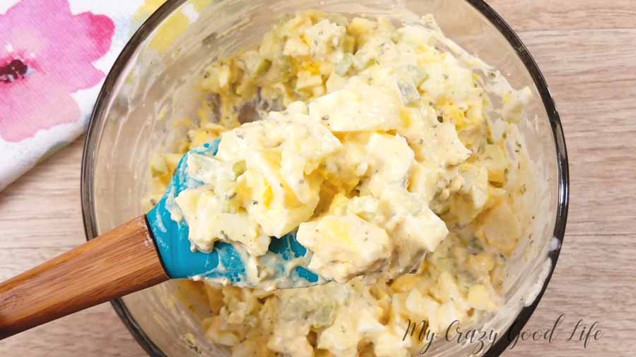 cooked egg salad in bowl with a blue spatula