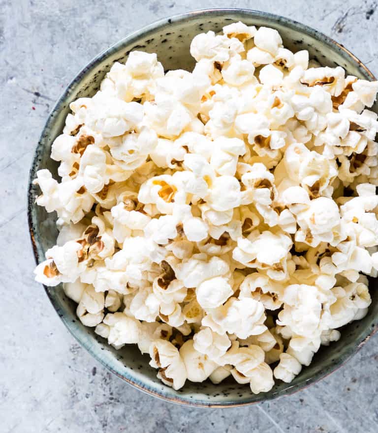 close-up of popcorn in a rusting white bowl with blue design on a marble table