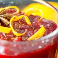cranberry sauce in a serving dish topped with orange peel and anise with naval orange in backround