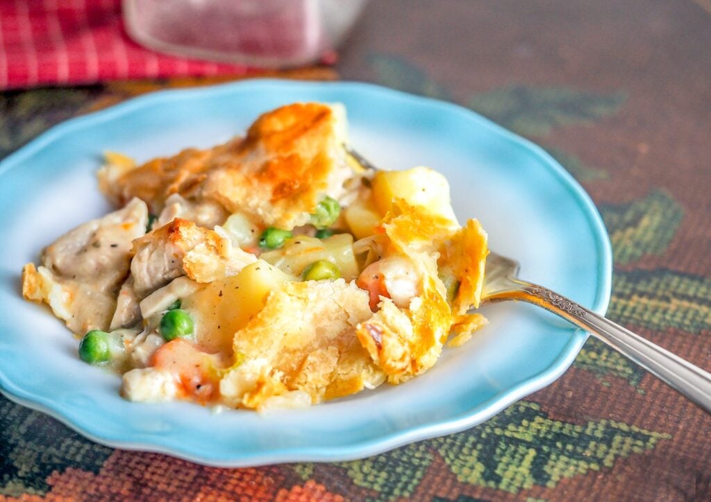 baked chicken pot pie on a blue edged ribbon plate on a table with a fork