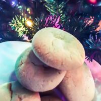 Close-up of sugar cookies on a white plant in front of a lighted christmas tree