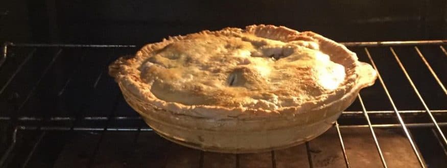 baked apple pie in the oven on a rack
