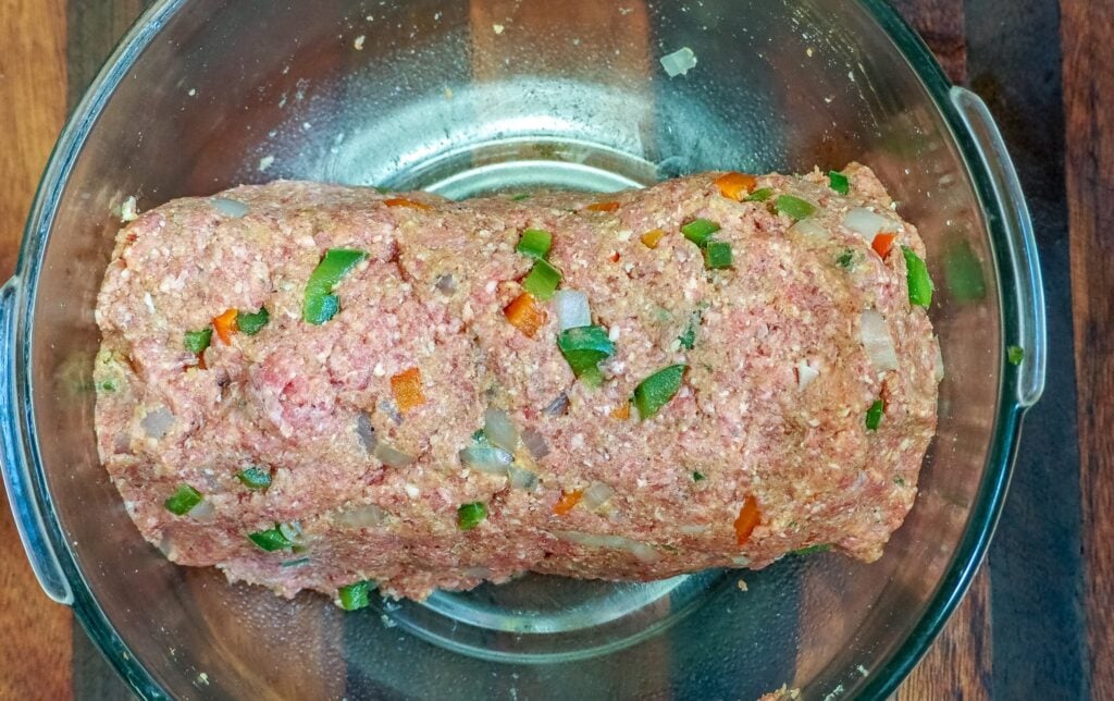 meatloaf mixture formed into a loaf in a large glass bowl on a wooden table