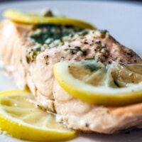 steamed herbed salmon on a plate with lemon slices