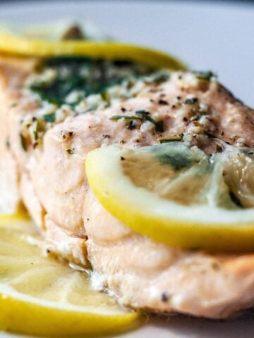 steamed herbed salmon on a plate with lemon slices