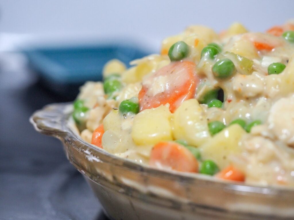 chicken pot pie filling piled high in a pie pan with a bottom crust