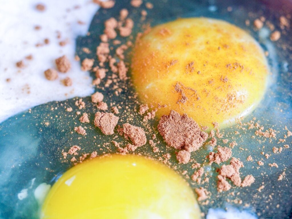 two raw eggs with milk and cinnamon in a bowl