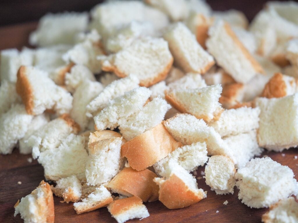 cubed white bread sitting on a dark cutting board