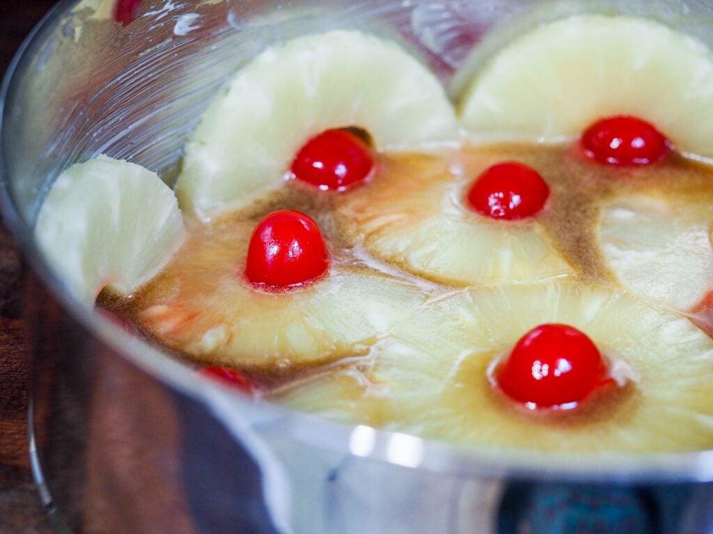 close up view of pan with sliced pineapples with cherries