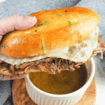 french dip sandwich being dipped in au jus