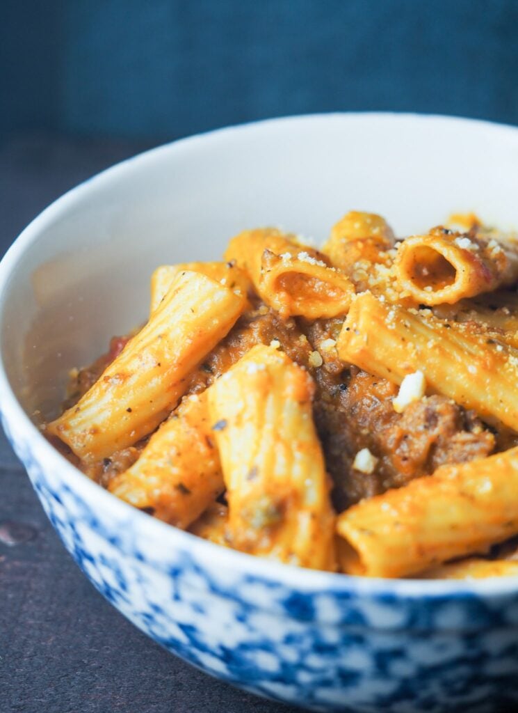 bowl of ziti in blue and white bowl on brown counterop