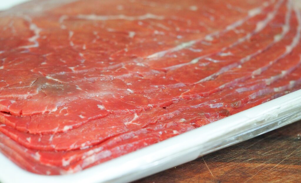 milanesa cut beef in butcher wrapping on cutting board