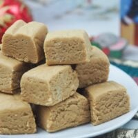 cut peanut butter fudge on white place on top of quilted christmas ornaments in front of christmas cards