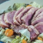 cooked and sliced corned beef and cabbage in white enameled cast iron pan