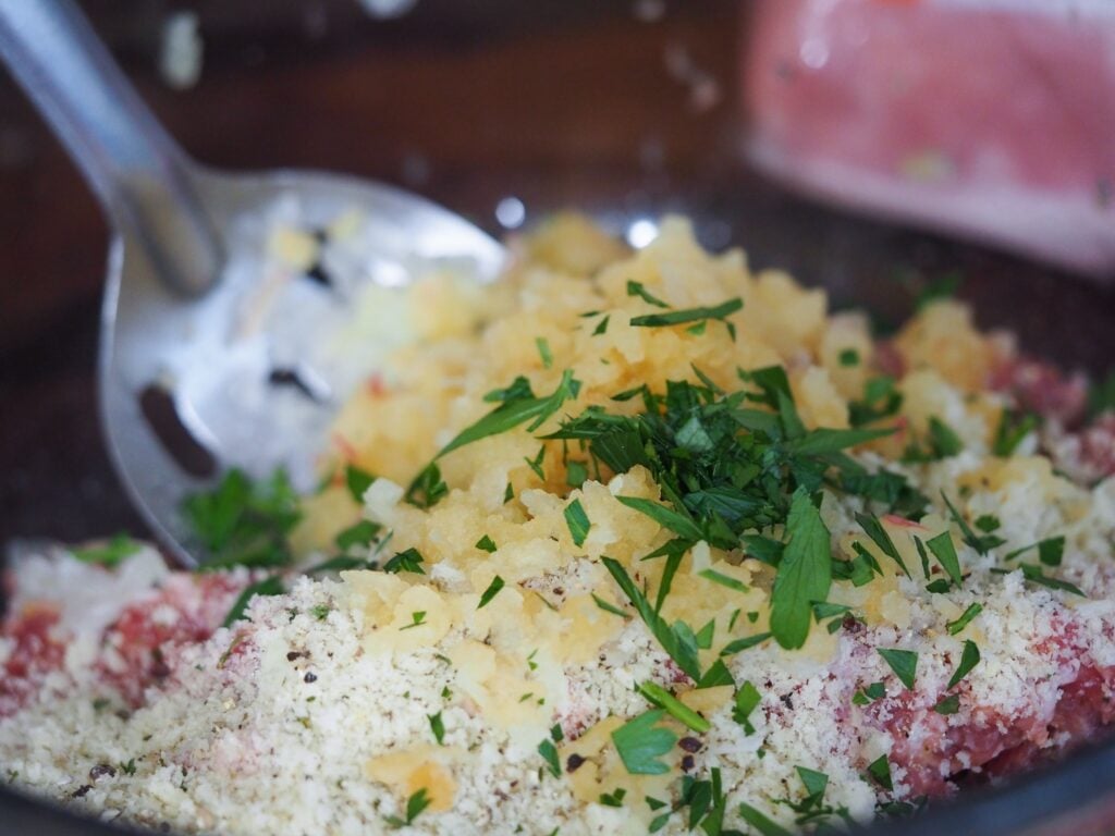 sausage stuffing in small clear mixing bowl with metal mixing spoon