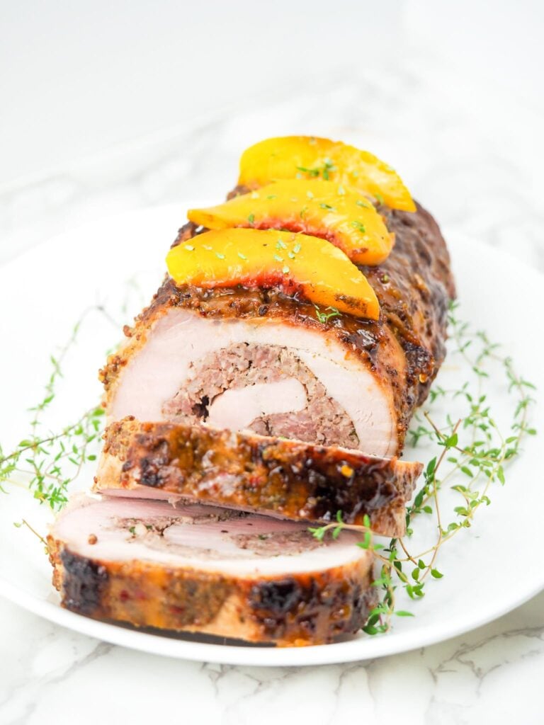 Vertical image of sliced stuffed pork loin on marble countertop