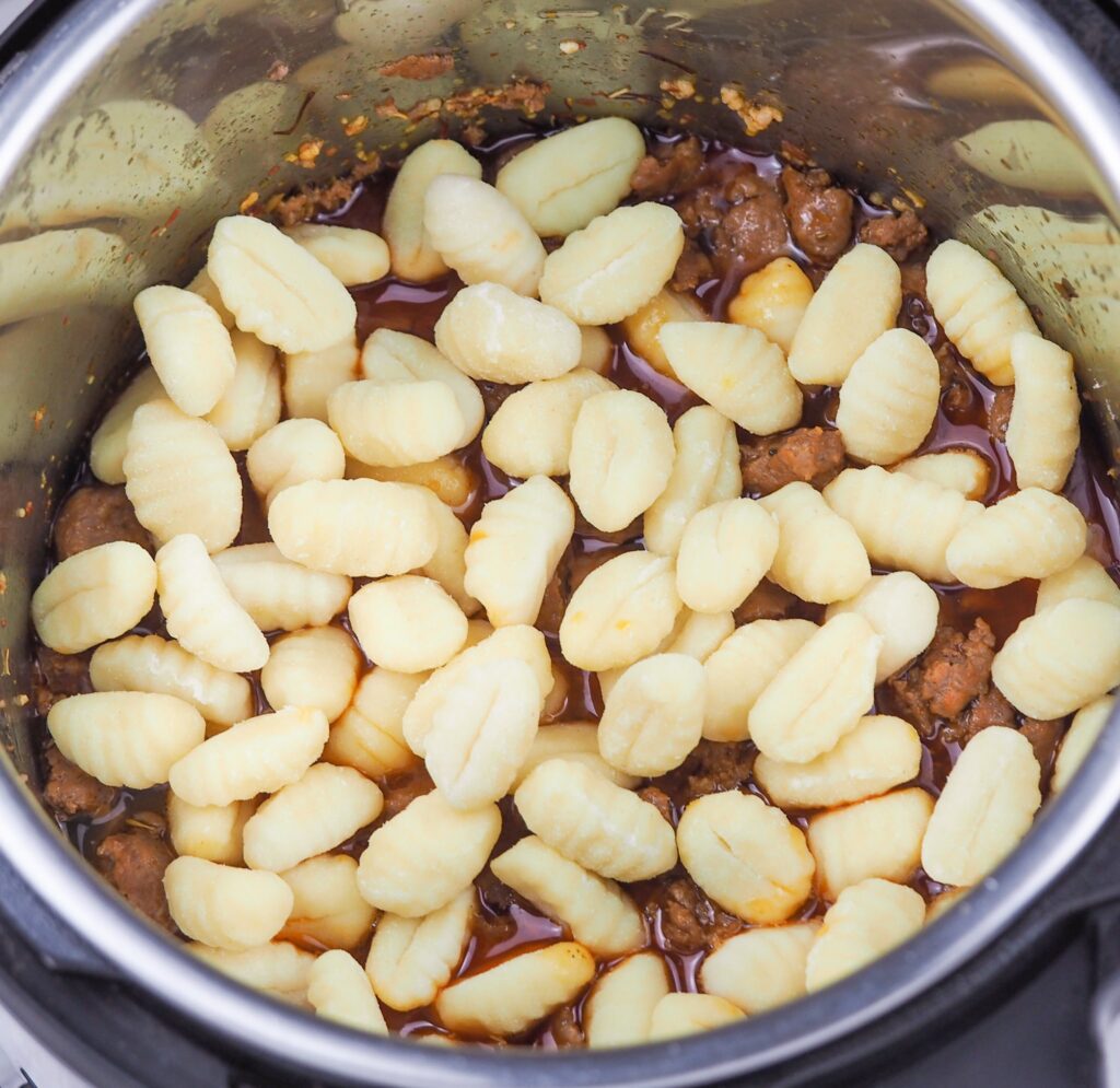 overhead view of sausage layered with gnocchi on top in the Instant Pot