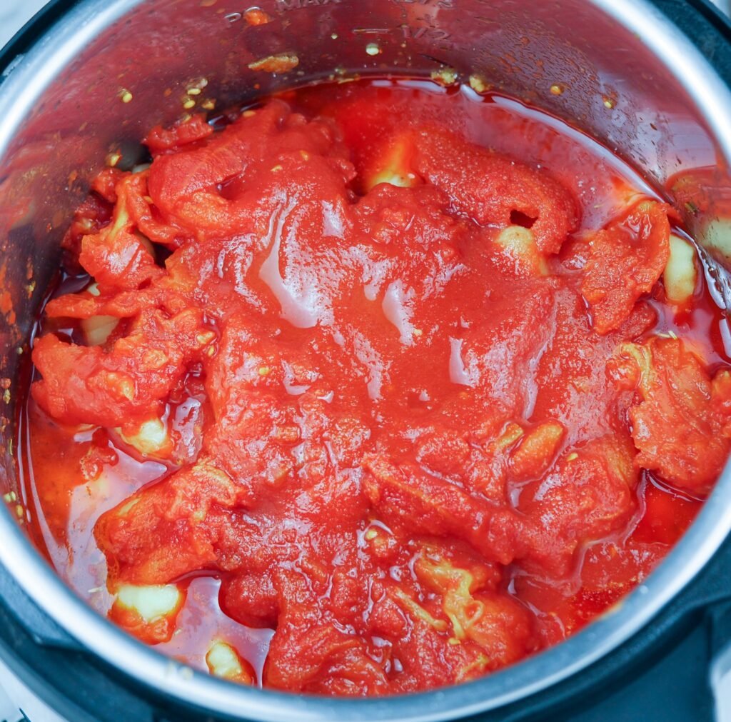 overhead view of tomatoes on top of a bed of Italian sausage and gnocchi in the Instant Pot