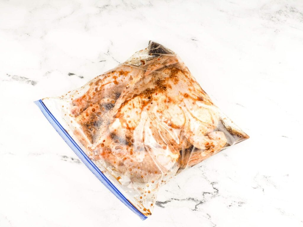overhead view of whole chicken in plastic bag covered in marinade