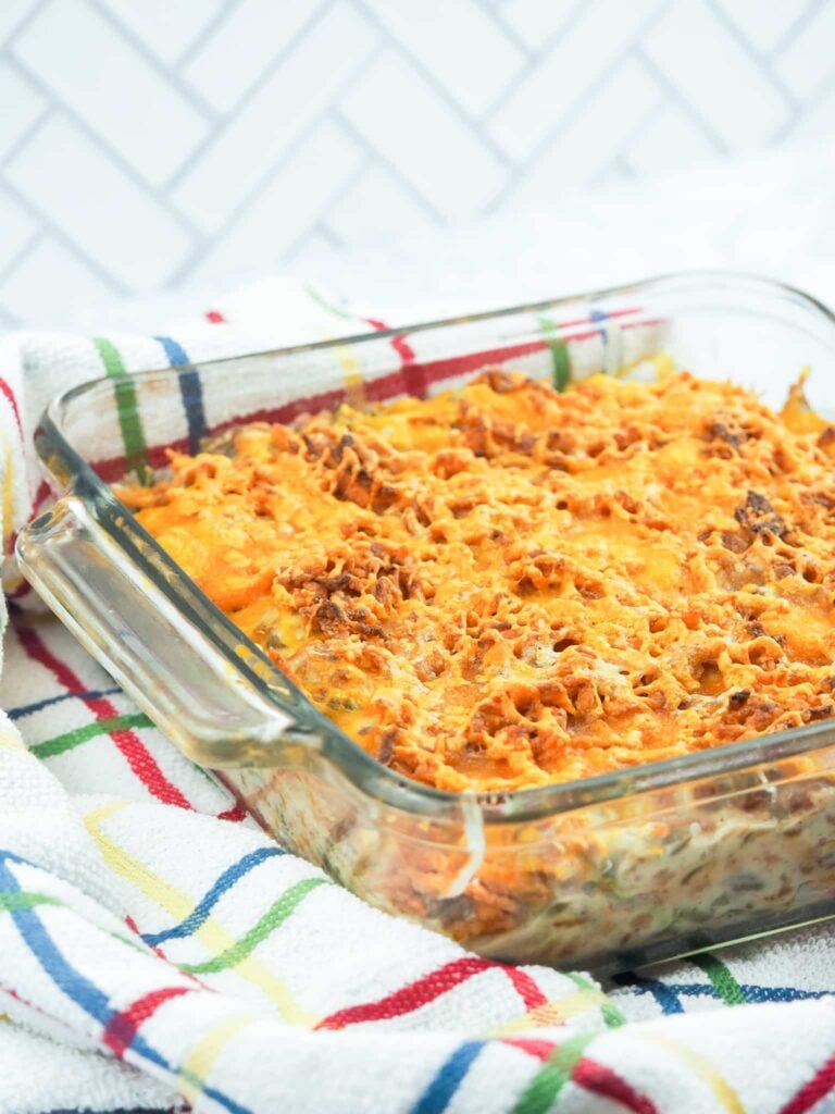 baked green bean casserole in glass baking dish on multi colored towel