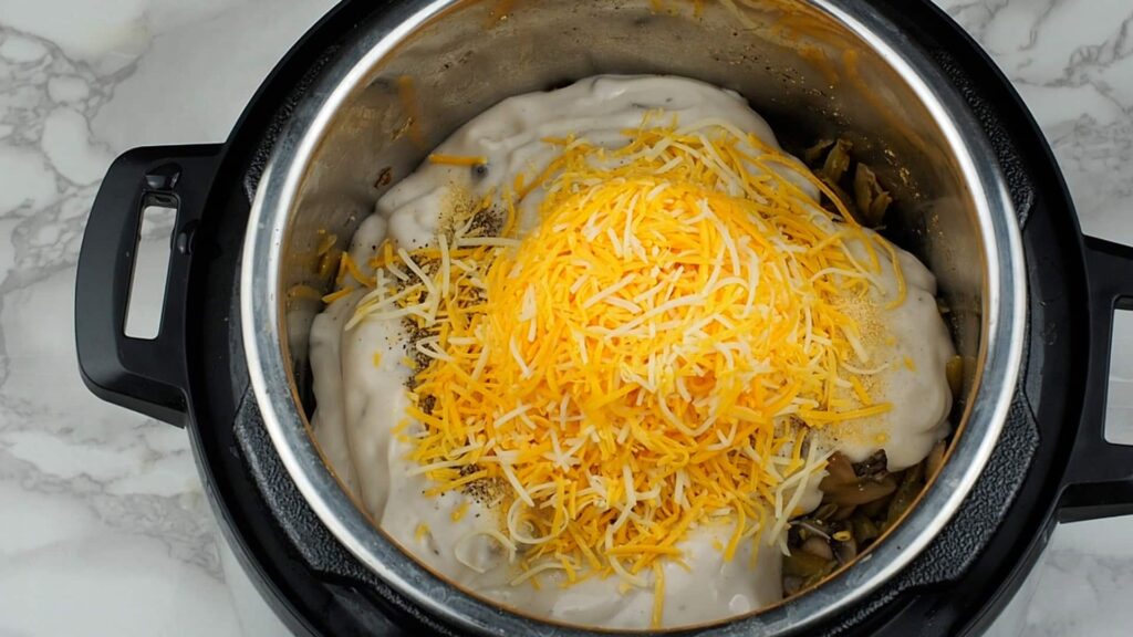 overhead view of all green bean casserole ingredients in instant pot with cheese on top