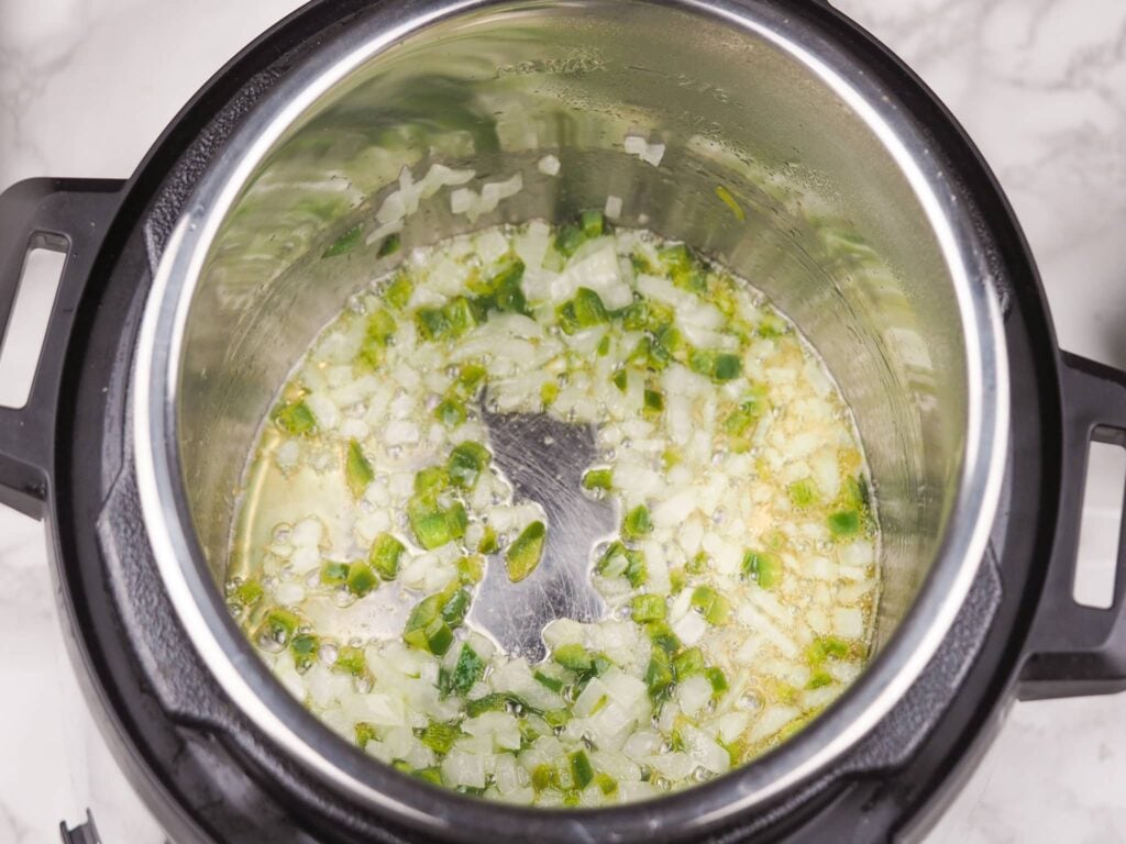 overhead view of finely diced jalapeno and onion cooking in pressure cooker