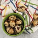 quail eggs in green cup on grey counter with multi colored towel