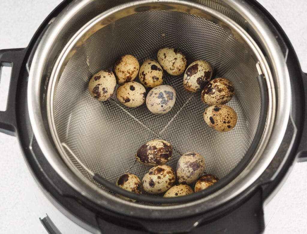 raw quail eggs in steamer basket inside an instant pot