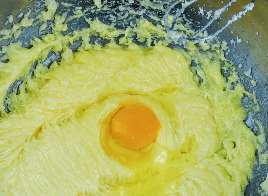 cake batter in metal bowl with raw egg in center 