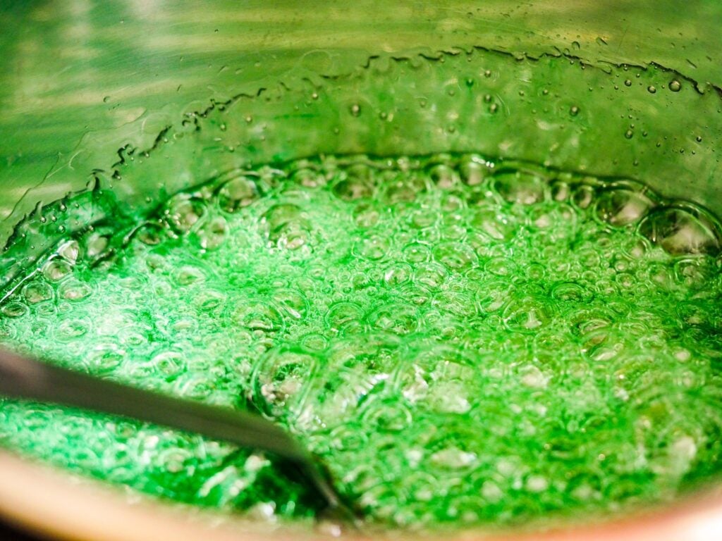 hard tack candy boiling in pot with green food dye
