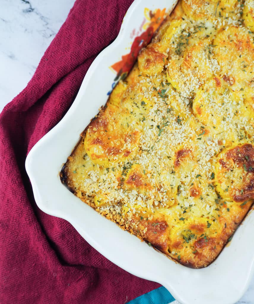 summer squash casserole in baking dish wrapped in a magenta towel