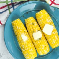 three ears of cooked corn on blue plate