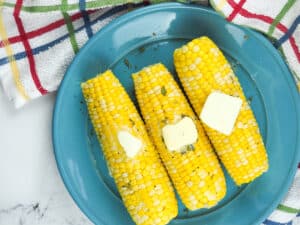 three ears of cooked corn on blue plate