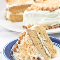 sliced cake on white plate with blue rim with whole cake in background