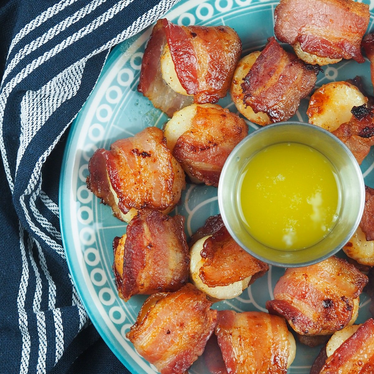 bacon wrapped scallops on plate with dipping butter