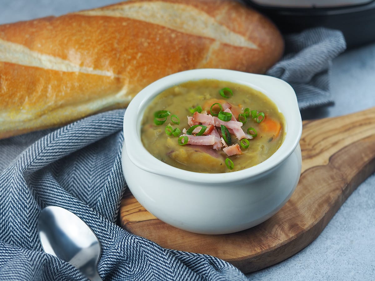 split pea soup on cutting board next to bread and spoon