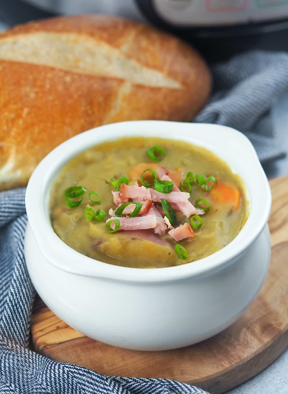 split pea soup in white crock bowl next to bread loaf