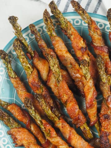 asparagus wrapped with bacon on blue and white plate