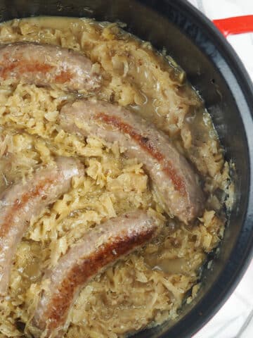 bratwurst nestled in sauerkraut in Dutch oven