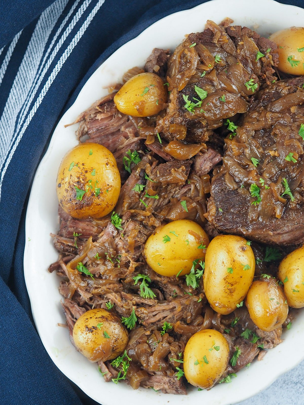 french onion pot roast on white platter with roasted potatoes
