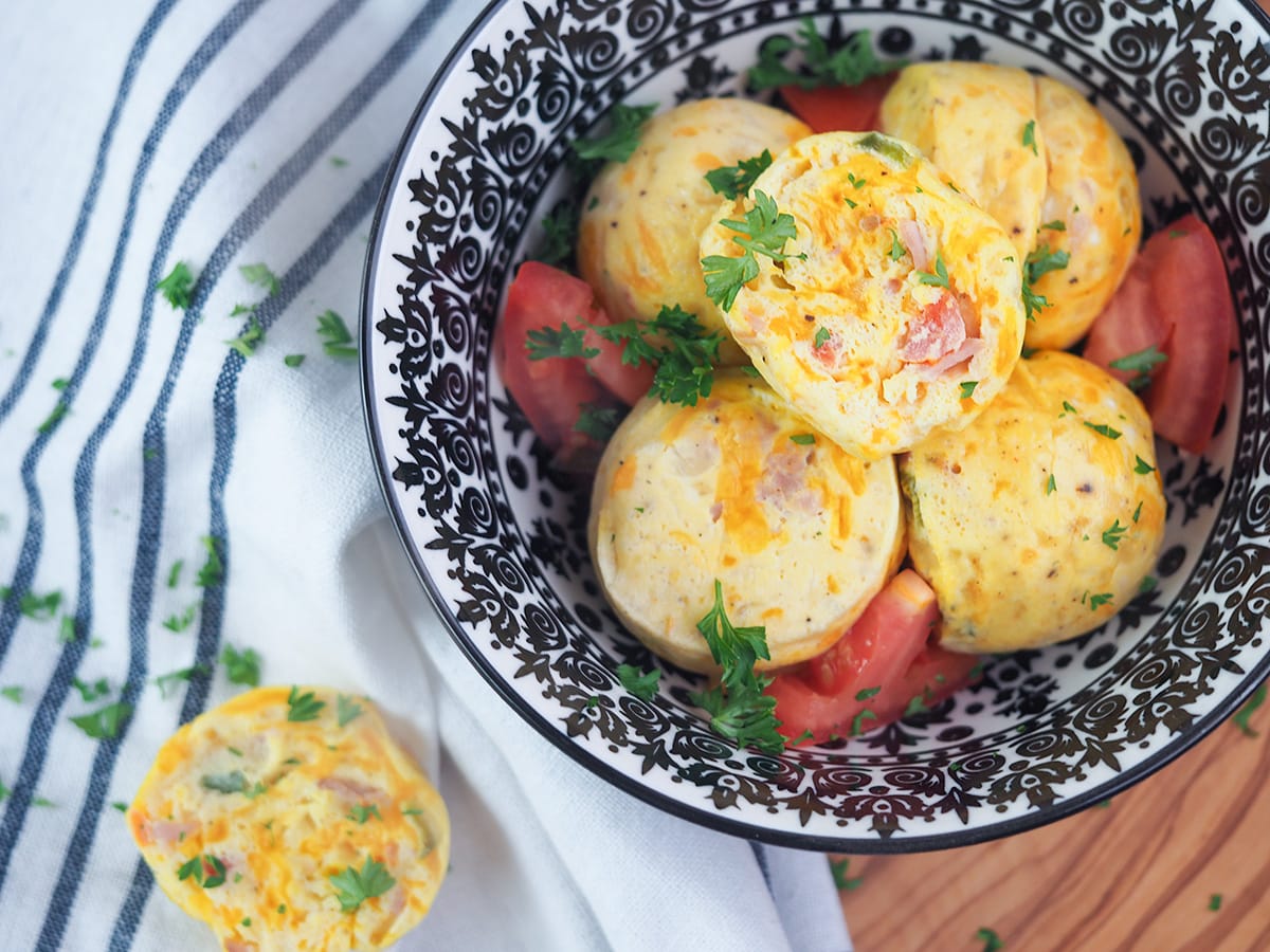 egg bites in white bowl with black designs with cut tomatoes
