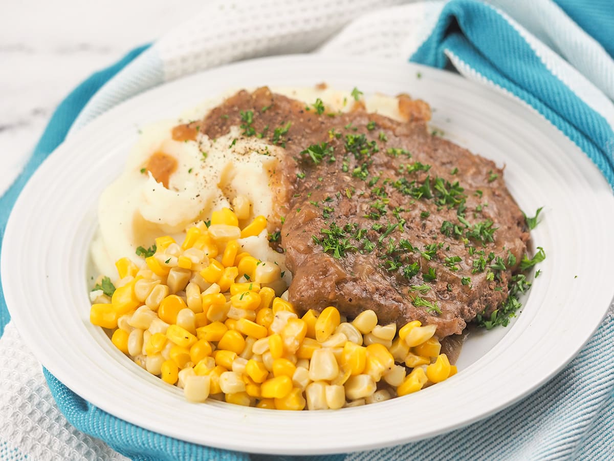 cube steak on plate with mashed potatoes and corn