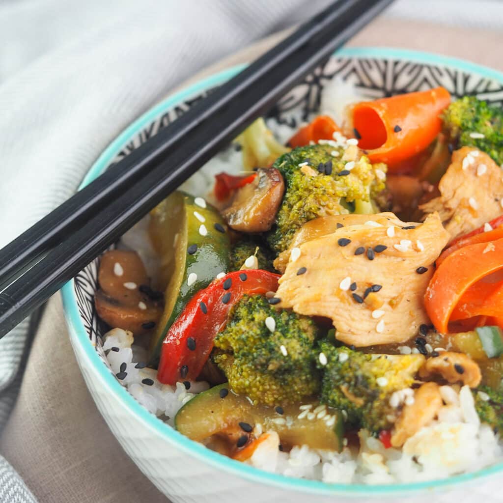 Stir fry with chicken and vegetables on top of rice in a bowl