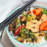 Stir fry with chicken and vegetables on top of rice in a bowl