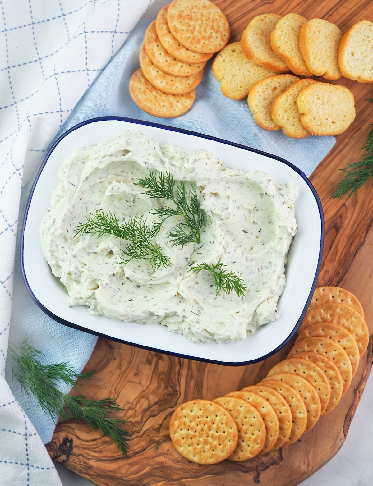 homemade boursin cheese on cutting board with dill and cracker