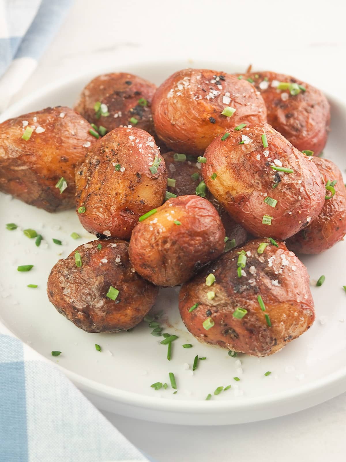 roasted red potatoes salted with chives on white plate