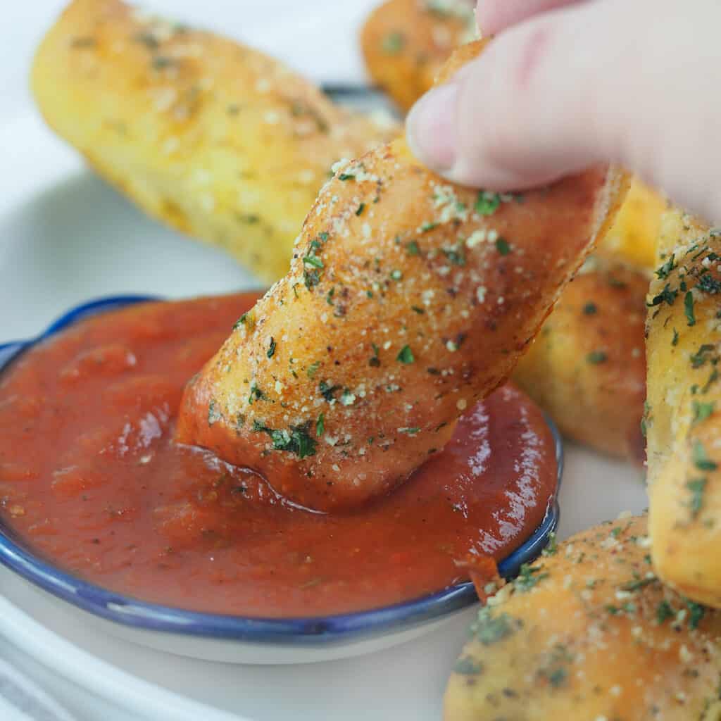 breadstick being dipped in marinara sauce