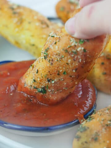 breadstick being dipped in marinara sauce