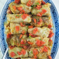 cabbage rolls on blue and white platter with serving spoon